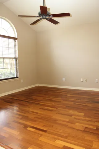 an empty room with wooden floor and windows