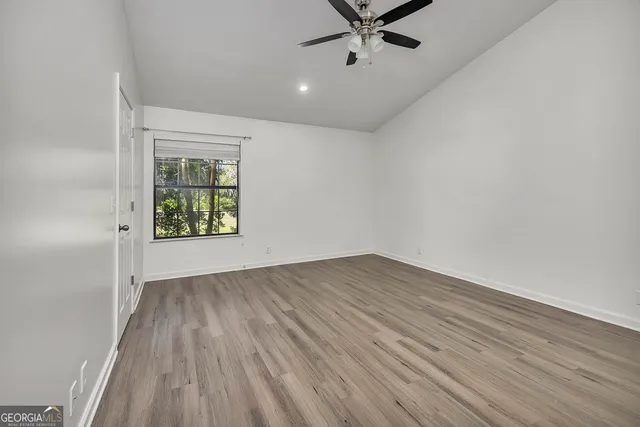 an empty room with a hardwood and ceiling fan