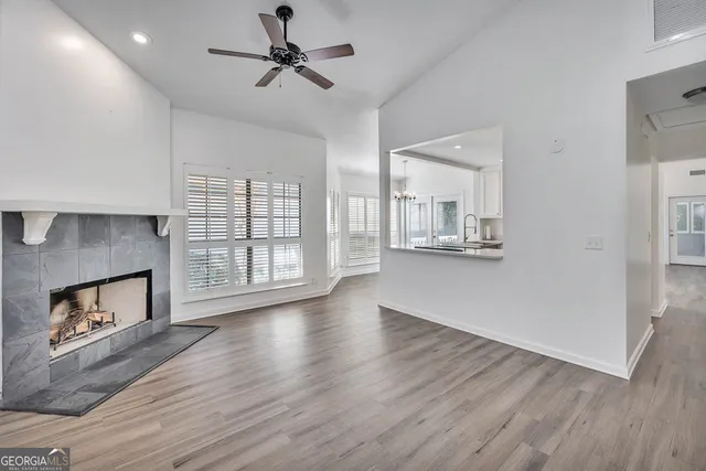 an empty room with wooden floor chandelier fan and windows