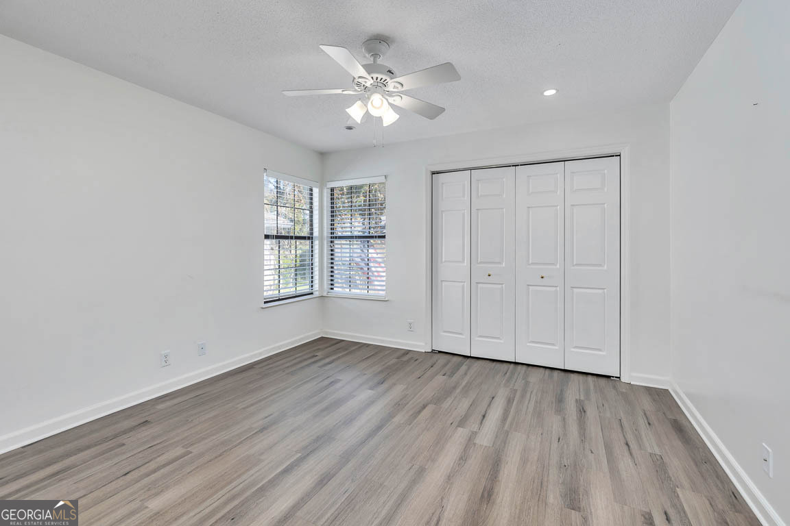 3 Bay Tree Court West St. Simons, GA 31522 - Photo 26 of 36 an empty room with wooden floor chandelier fan and windows