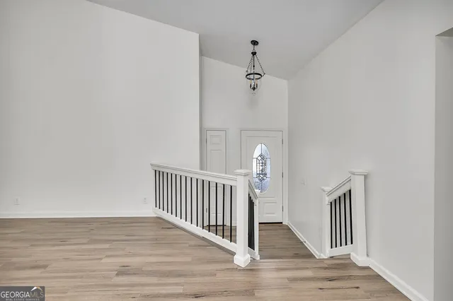 a view of a hallway with wooden floor and a chandelier