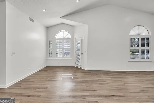 an empty room with wooden floor and windows