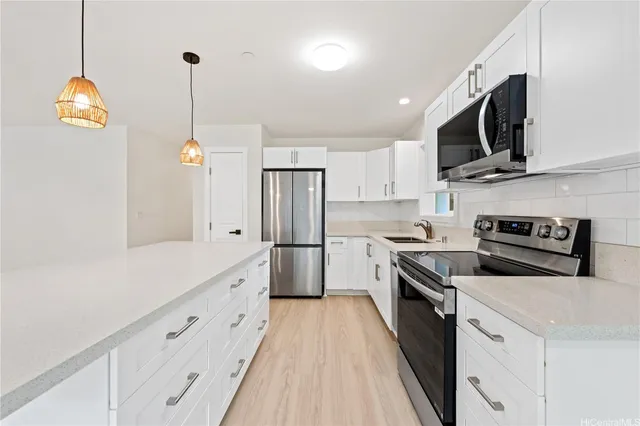 a kitchen with stainless steel appliances white cabinets and a wooden floor
