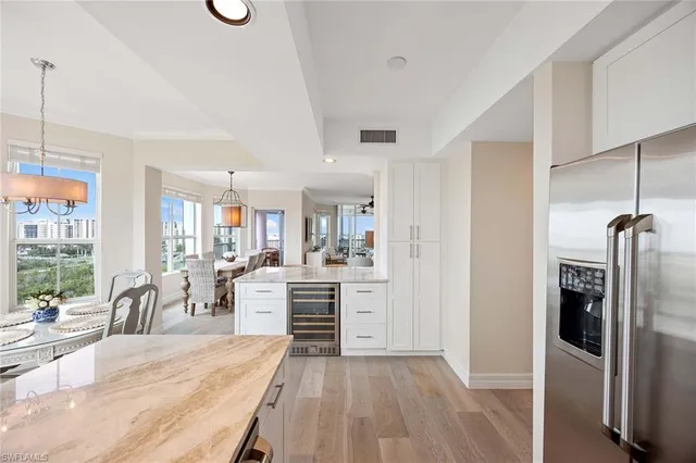 a view of a kitchen with kitchen island a large window a sink stainless steel appliances and cabinets
