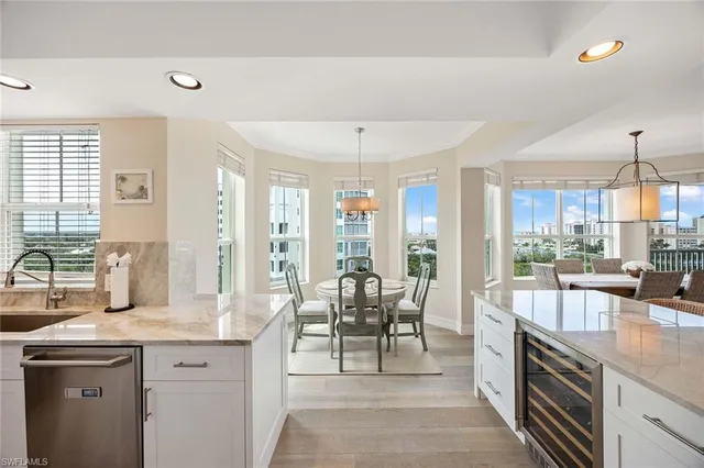 a large kitchen with granite countertop a large counter top furniture a stove and a chandelier