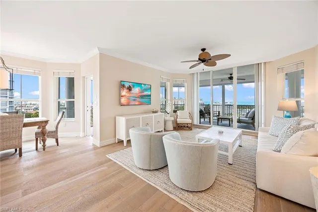 a living room with couches and kitchen view with wooden floor