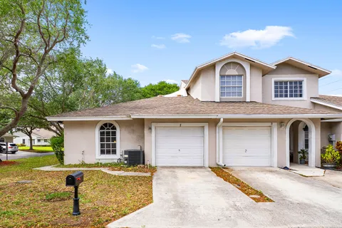a front view of a house with a garden and tree