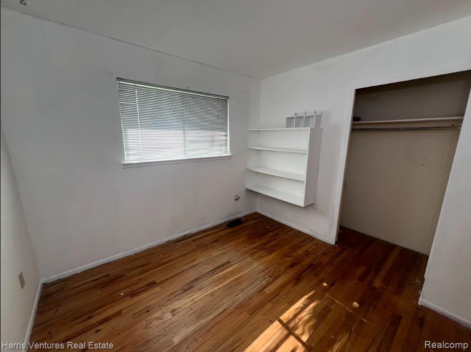 28482 Sutherland Avenue Warren, MI 48088 - Photo 13 of 25 Bedroom #1 with wood-finish flooring, a window with horizontal blinds, built-in wall shelving, and an open closet