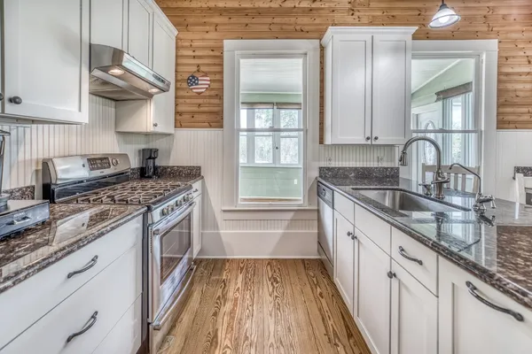 a kitchen with stainless steel appliances granite countertop a sink cabinets and wooden floor