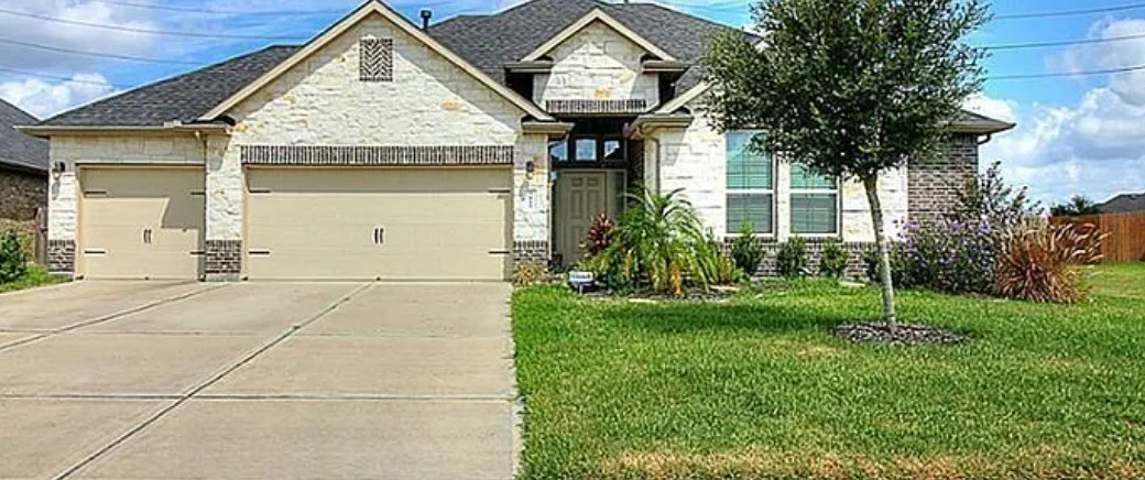 a view of a house with brick walls and a yard with plants