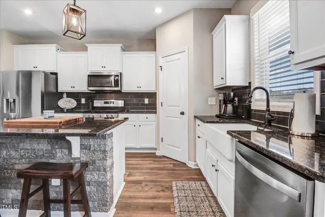 a kitchen with stainless steel appliances granite countertop a refrigerator a stove a sink a microwave and a refrigerator