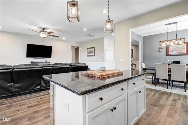 a kitchen with kitchen island granite countertop wooden floors and white cabinets