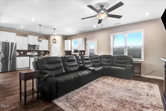 a living room with furniture kitchen view and a wooden floor