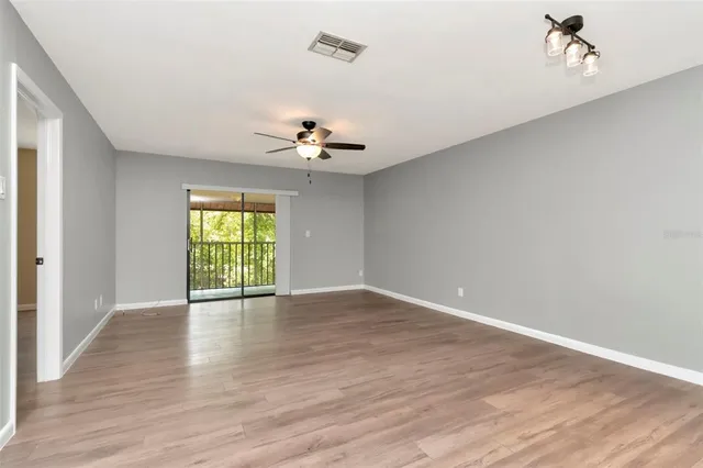 a view of an empty room with a window and wooden floor