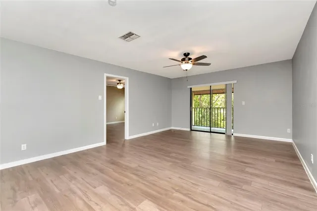 a view of an empty room with a window and wooden floor