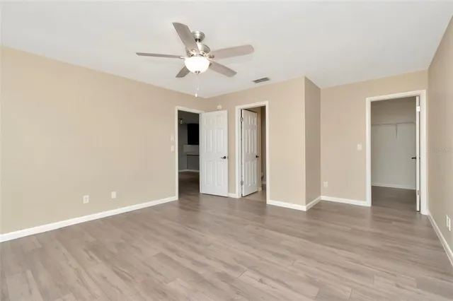 an empty room with wooden floor and ceiling fan