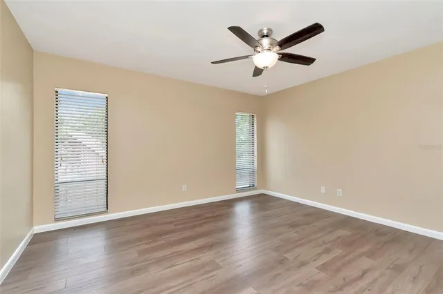 an empty room with wooden floor and ceiling fan