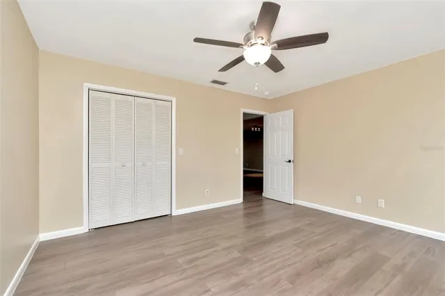 an empty room with wooden floor fan and windows