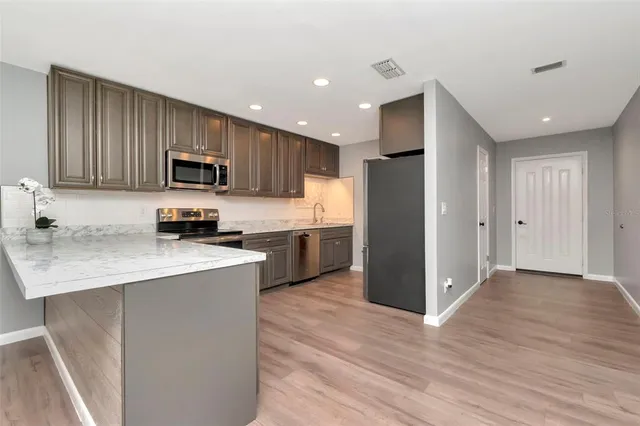 a kitchen with kitchen island a refrigerator and a stove top oven