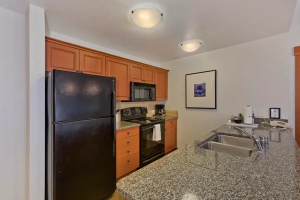 a kitchen with stainless steel appliances granite countertop a refrigerator and a stove top oven