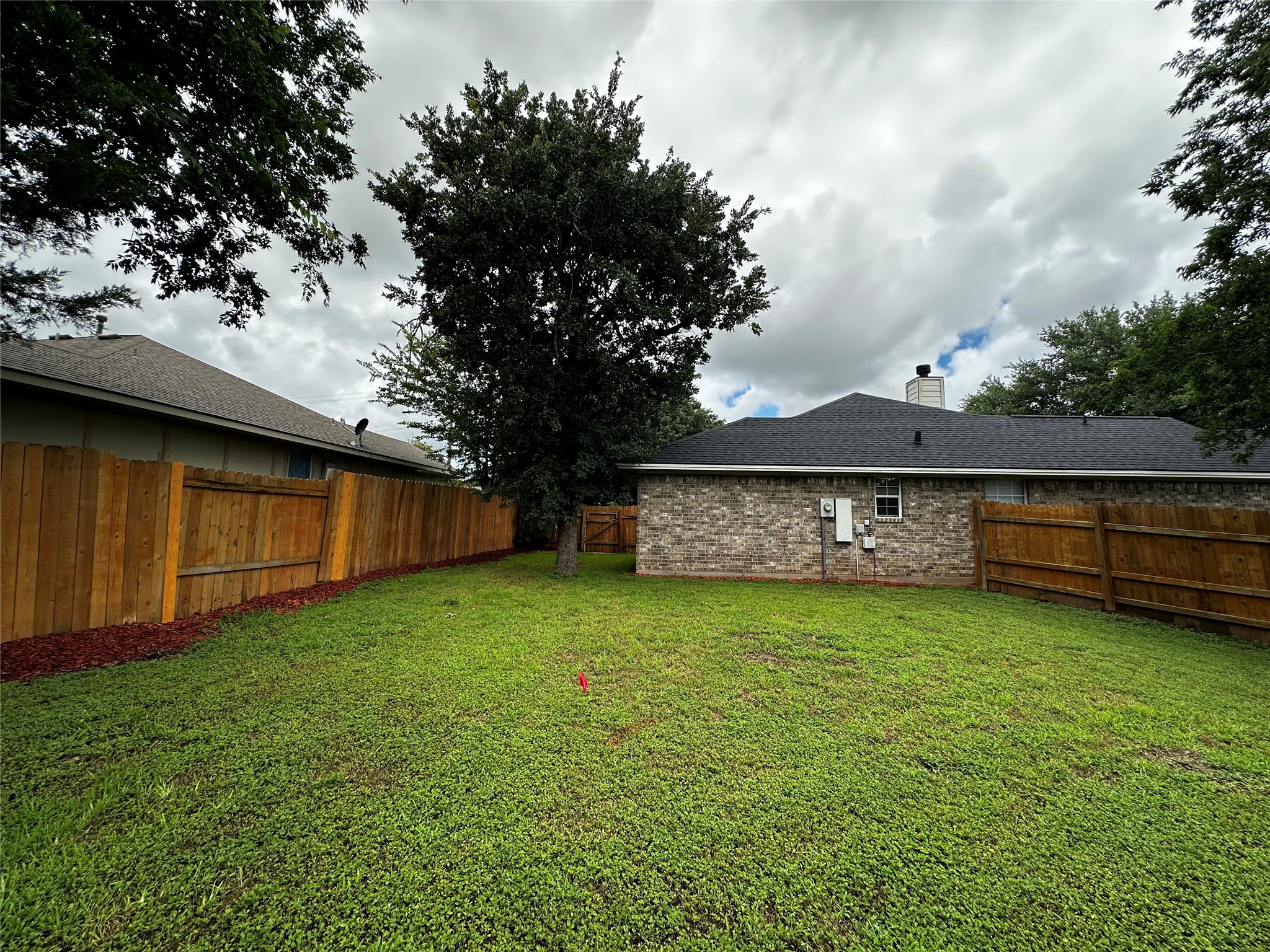 1400 Prairie Drive Bryan, TX 77802 - Photo 16 of 18 A generous grassy lawn unfolds, bordered by sturdy wood fencing, offering ample space for outdoor enjoyment.