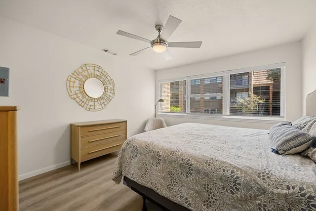a bedroom with a bed dresser and a large window
