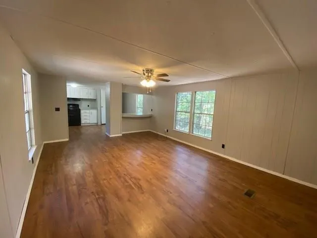 an empty room with wooden floor and windows
