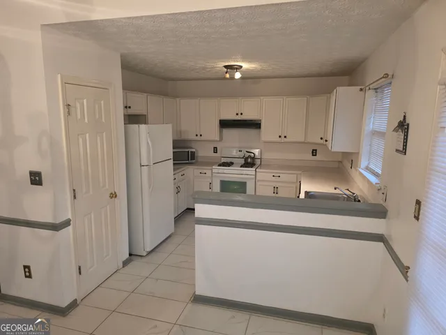 a kitchen with stainless steel appliances granite countertop a refrigerator sink and white cabinets