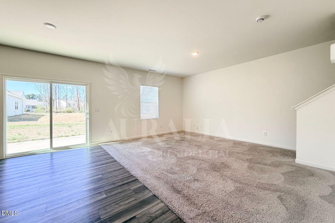 937 Berkeley Glen Road Zebulon, NC 27597 - Photo 5 of 35 an empty room with wooden floor and windows