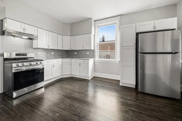 a kitchen with granite countertop a refrigerator stove and wooden floor