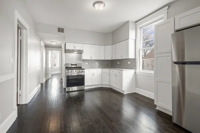a kitchen with a refrigerator a stove top oven and wooden floor
