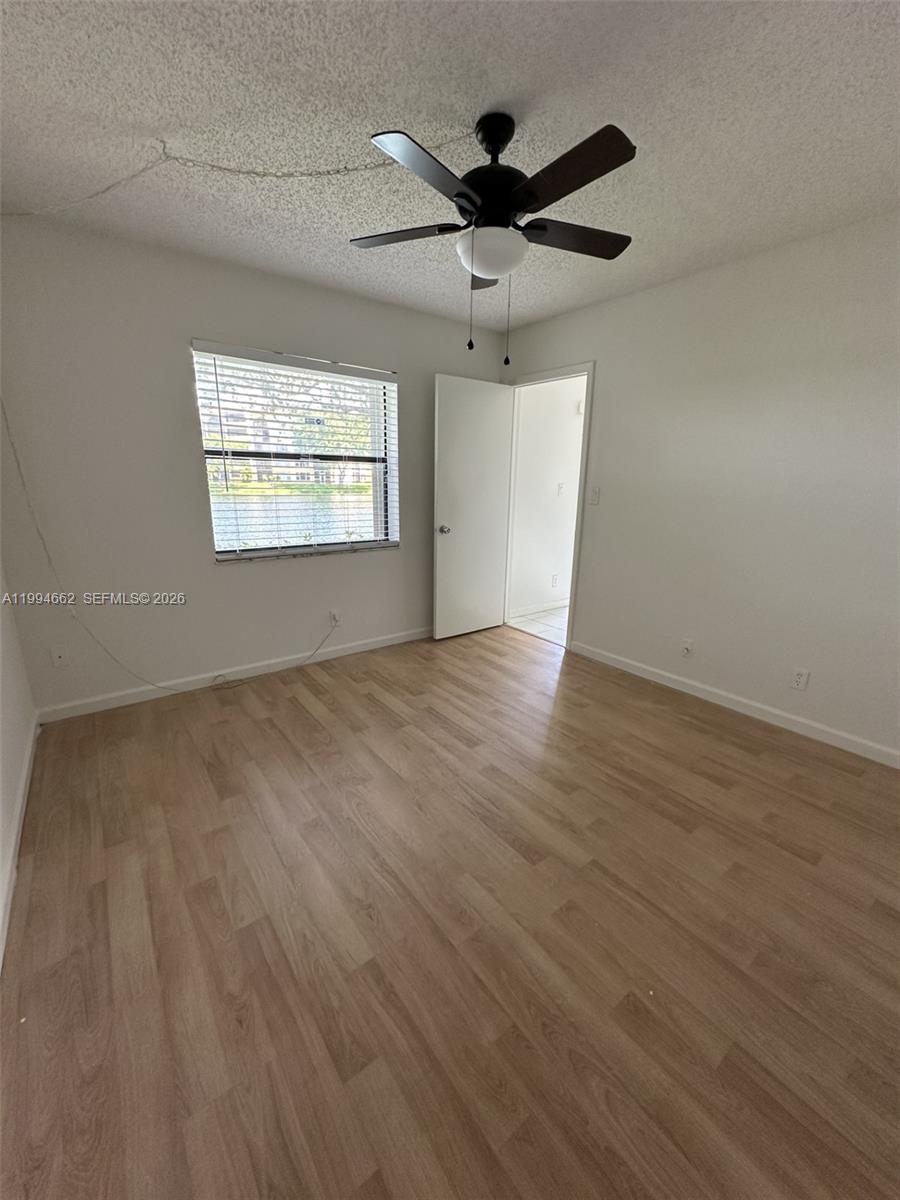 10003 Winding Lake Road, Unit 103 Sunrise, FL 33351 - Photo 4 of 12 an empty room with wooden floor ceiling fan and windows