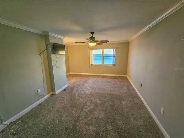 an empty room with windows and ceiling fan