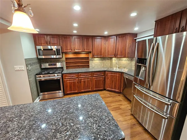 a kitchen with stainless steel appliances granite countertop a refrigerator and a sink