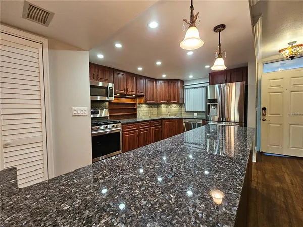 a kitchen with kitchen island granite countertop wooden cabinets a refrigerator and a stove