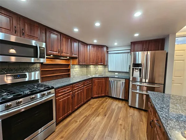 a kitchen with kitchen island granite countertop wooden cabinets stainless steel appliances and a counter space