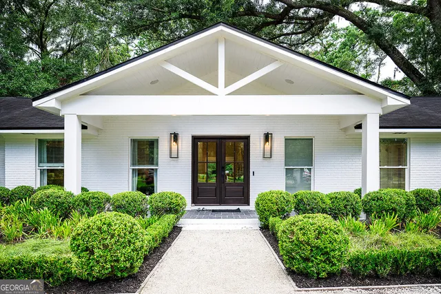 a view of a house with brick walls plants and large trees