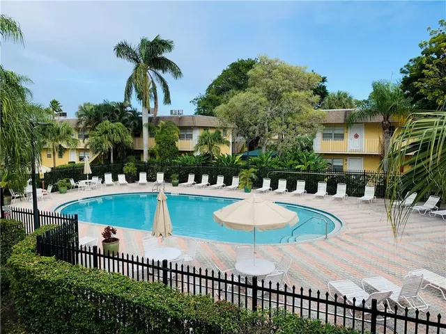 a front view of a house with swimming pool and glass top table and chairs