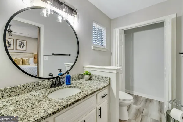 a bathroom with a granite countertop toilet a sink and a mirror