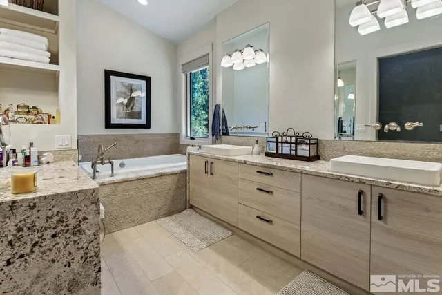 a spacious bathroom with double vanity a mirror a bathtub and a sink