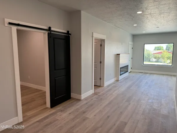 an empty room with wooden floor closet and windows