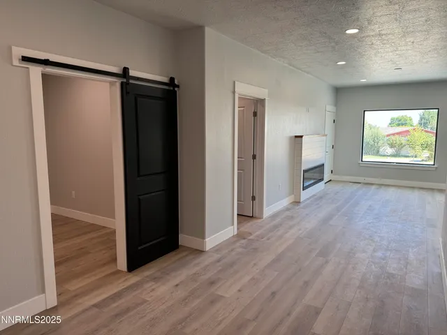 an empty room with wooden floor closet and windows