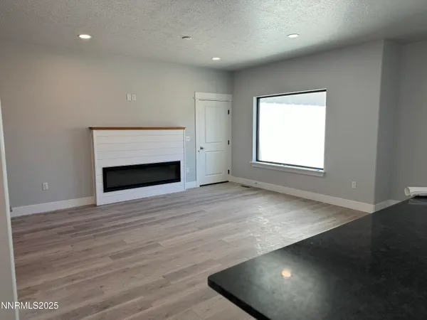 an empty room with wooden floor fireplace and windows