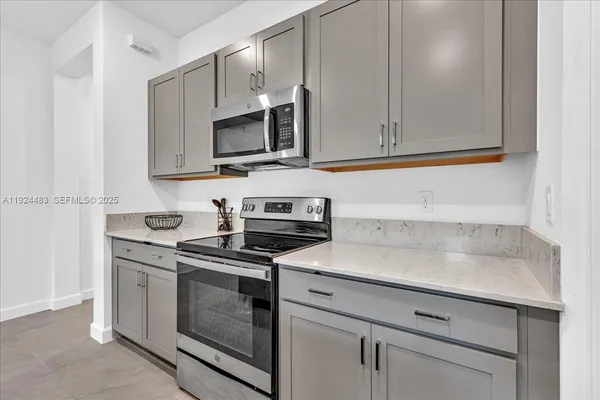 a kitchen with stainless steel appliances granite countertop white cabinets and a stove top oven