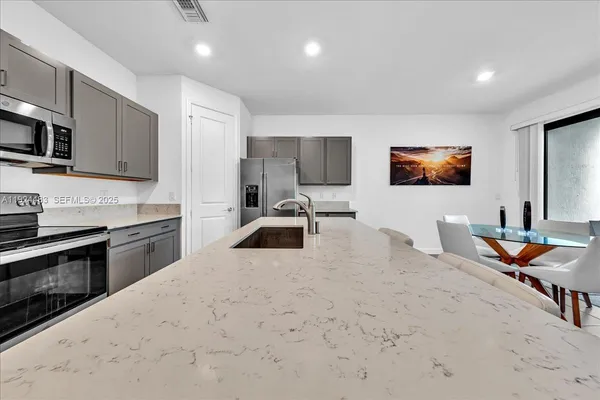 a kitchen with stainless steel appliances kitchen island granite countertop a sink and a stove