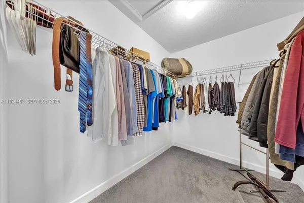 a view of walk in closet with clothes and shoes