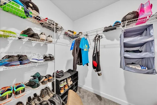 a view of walk in closet with clothes and shoes