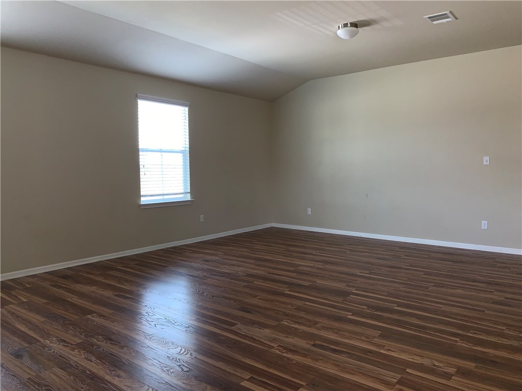 151 Chickadee Cove Kyle, TX 78640 - Photo 13 of 29 an empty room with wooden floor and windows