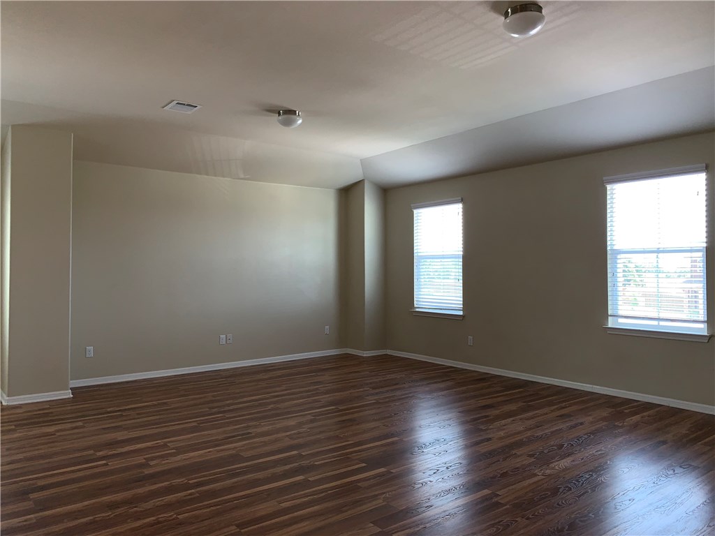 151 Chickadee Cove Kyle, TX 78640 - Photo 14 of 29 an empty room with wooden floor and windows