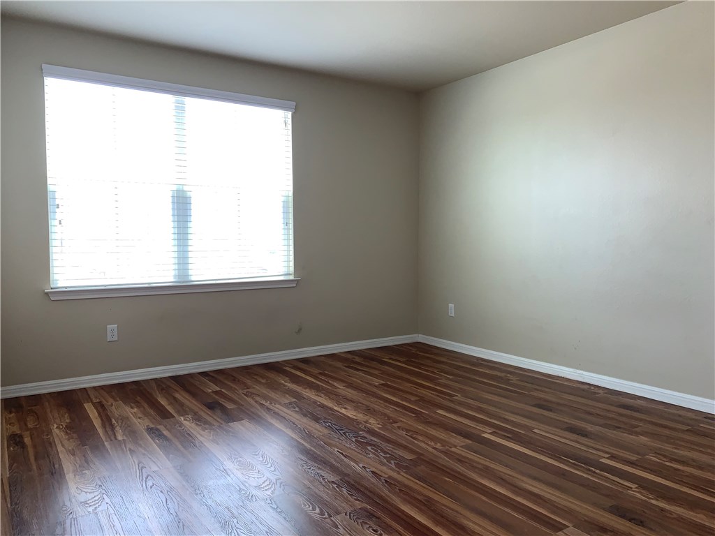 151 Chickadee Cove Kyle, TX 78640 - Photo 15 of 29 a view of an empty room with wooden floor and a window